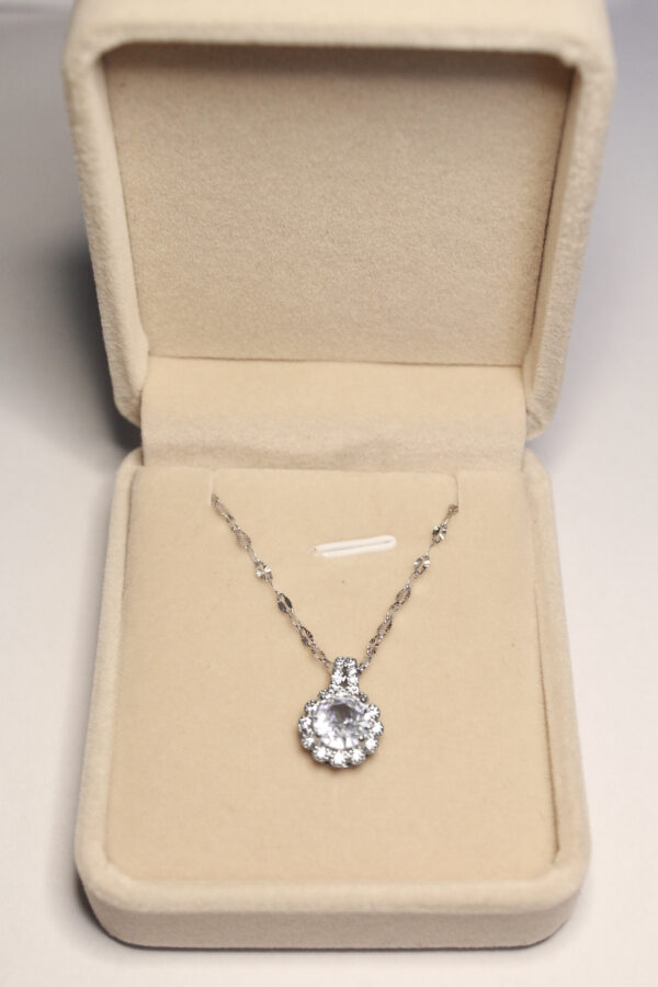 Colier Celeste Noire prezentat în cutie cadou elegantă bej, bijuterie cu pandantiv rotund argintiu.