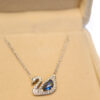 Colier argintiu cu pandantiv lebădă albastru în cutie elegantă de bijuterii.