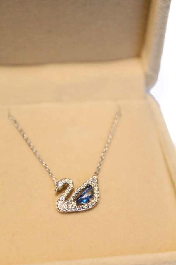 Colier argintiu cu pandantiv lebădă albastru în cutie elegantă de bijuterii.